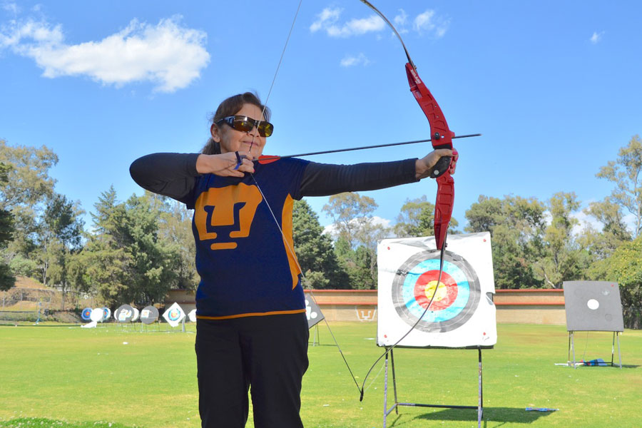 Maestra Cati arquera de tacto posa con arco y flecha representando al equipo especial de la Universidad nacional Autónoma de México UNAM